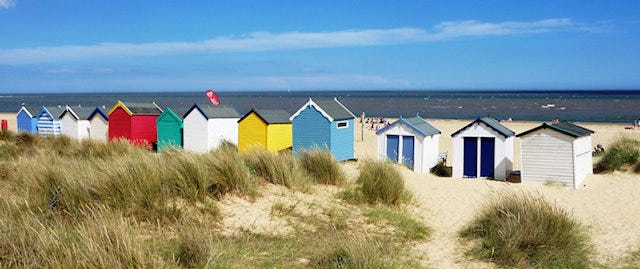 Colourful beach huts overlook the beach and sea