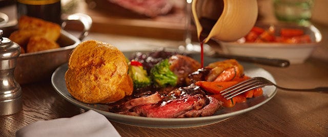 Gravy being poured on a roast beef dinner