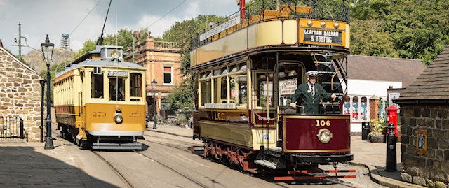 Two old trams with suited conductors on