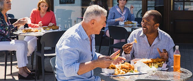 People sitting outside enjoying fish and chips and drinks