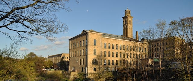 A blocky, imposing building with a tower, that is the Salts Mill