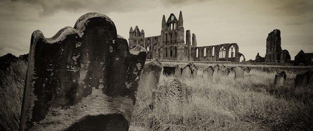 Black and white photo of Whity Abbey with gravestones in the foreground