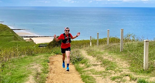 James running up a coastal path on a sunny day