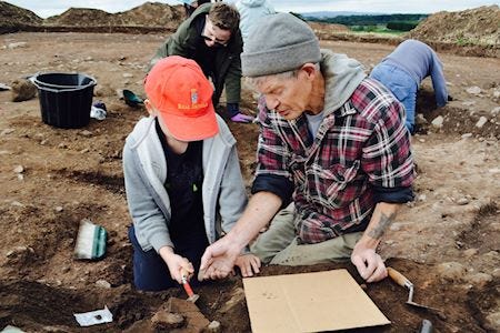 Expert teaching a young boy how to search through soil