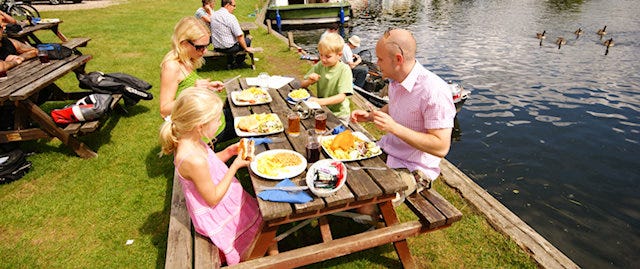 Family sitting at picnic bench next to river