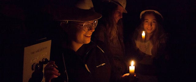 Children's faces illuminated by candlelight at the Peak District Mining Museum