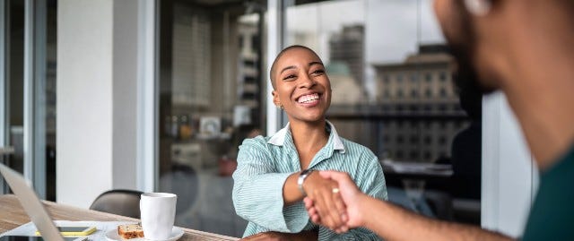 Two people shaking hands at desk