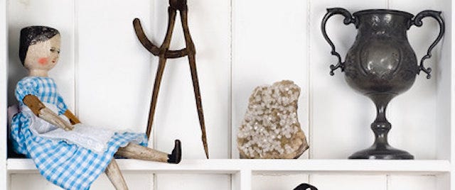 Museum objects on a shelf, including a small wooden doll