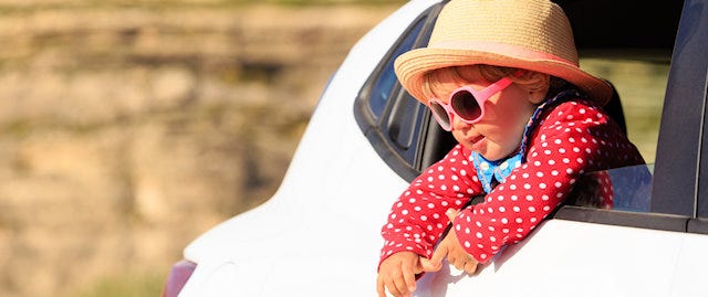 Child looking out of an open car window on a sunny day