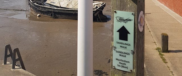 Footpath sign with the water in the background