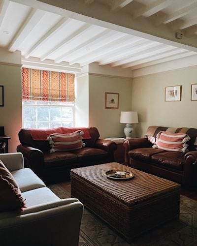 A cosy looking lounge with brown leather sofas and a beamed ceiling