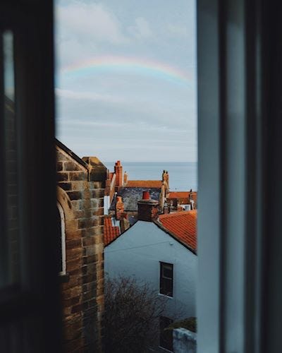 Overlooking rooftops at a rainbow over the sea