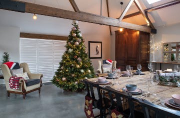 A dining room with a large table dressed for Christmas and a big decorated tree at the far end.