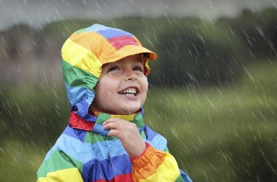 Boy in colourful raincoat in the rain 