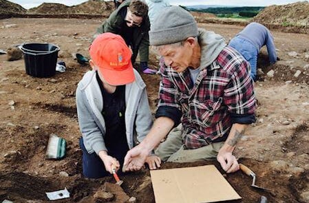 Expert teaching a young boy how to search the soil