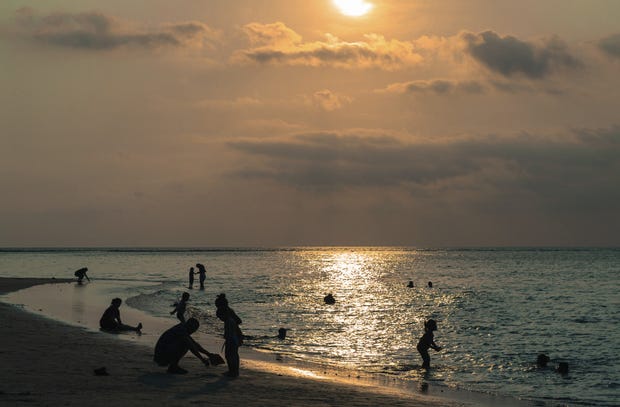 Sunset with people in silhouette in the foreground on the beach