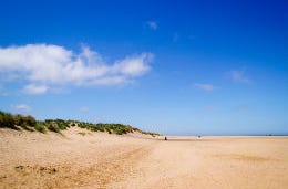 Sunny blue skies above a sandy beach on the Norfolk coast
