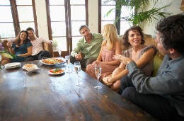 A large group of friends laughing and smiling sitting around a table.
