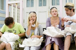 Friends eating classic British fish and chips by a beach hut.