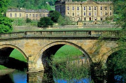 A grand county house with a pretty bridge in the foreground