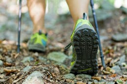 Close-up of woman's hiking boots as she walks with poles in the fells.