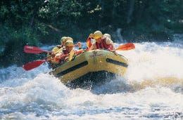 Friends grinning as they go white water rafting on some crazy rapids on Tryweryn River