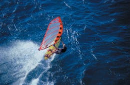 A water sports fan windsurfing with the deep blue ocean all around him.