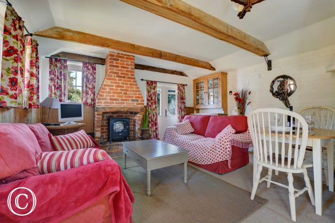 Cosy country cottage style living room, with beams and wood burner stove.