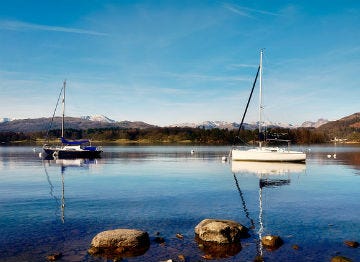 Two sailing boats with sails down on the calm lake water