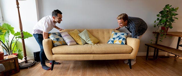 Two men moving a yellow sofa
